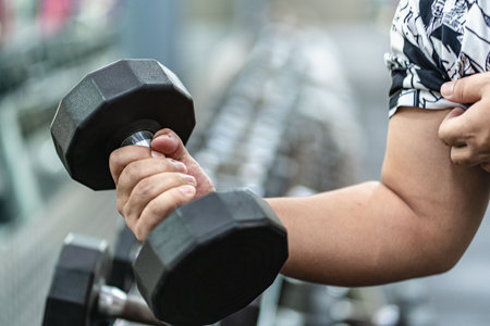 Weightlifter doing bench press exercising with dumbbells in gym lifting dumbbells near rack, male weightlifter doing biceps curls in fitness centerの写真素材