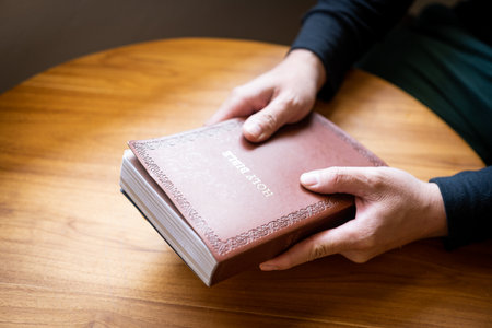 Male hand holding bible placed on wooden table Name of the book of prayers for blessings from God Bible laying on wooden table with copy spaceの写真素材