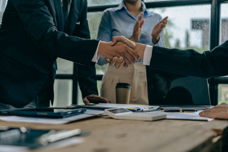 Two businessmen shaking hands making a money deal for handshake discussing successful financial business in conference roomの写真素材