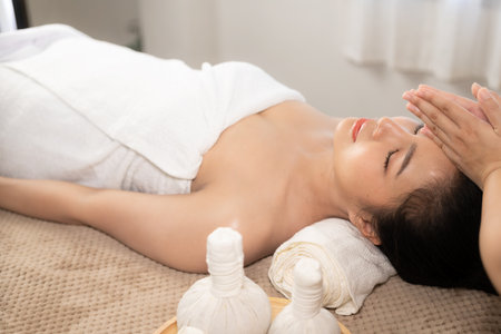 beautiful woman in spa environment Asian woman in bathrobe on sofa as she spas herself with massages and facials at home. concept of beautyの写真素材