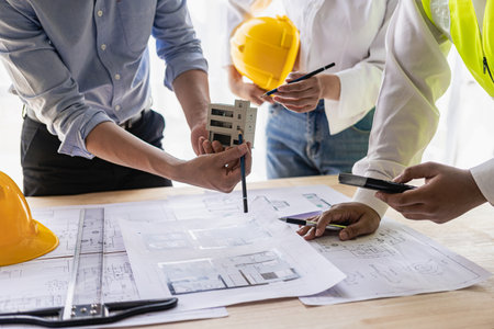 Engineers work as a team with blueprints for architectural plans. Engineer sketching construction...