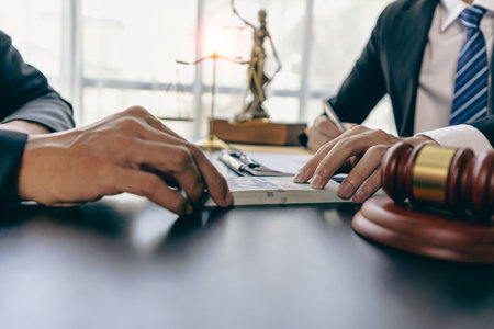 Bribery and corruption concept, bribery businessman giving money to male lawyer while helping with contract agreement to win court caseの写真素材