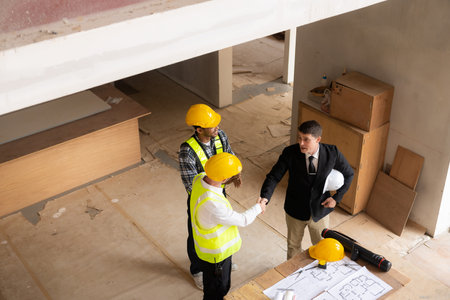 Businessman shaking hands with engineers in construction, construction site renovation concept,...