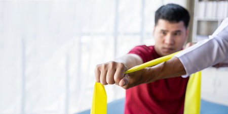 Young Asian man doing physiotherapy and seeking advice from muscle pain with shoulder, limbs in rehabilitation center.の写真素材