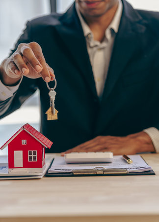 Handing over house keys and introducing houses Sales representatives handing over keys to customers New home buyers are approved home loans and insurance contracts.の写真素材