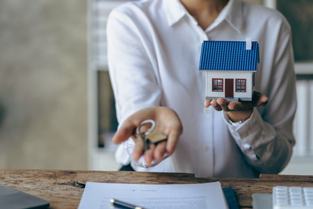 Handing over house keys and introducing houses Sales representatives handing over keys to customers New home buyers are approved home loans and insurance contracts.の写真素材