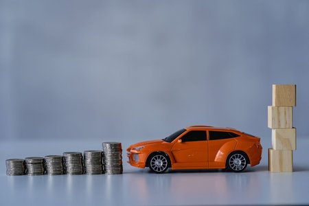Stacked wooden cubes and toy mini cars on table, saving and managing money for transport, economic crisis risk and problem concept.の写真素材