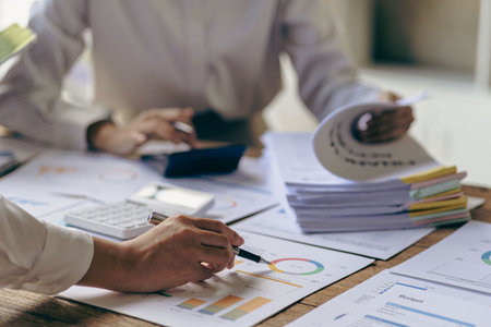 Asian business people meeting with laptop and graph papers to analyze and discuss situation on financial report in conference room investment advisor finance and accounting conceptの写真素材