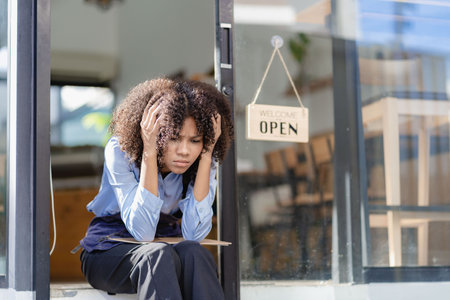 Barista Startup Coffee Shop African American female entrepreneur sitting sadly at the door of the...