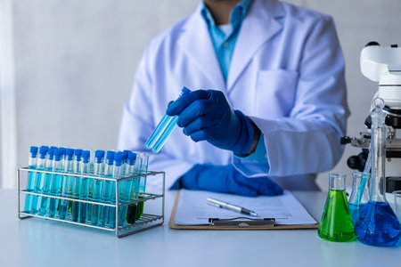 Medical or scientific researcher or male doctor looking at test tube of transparent solution in laboratory analysis Test tube with blue liquid in the laboratoryの写真素材