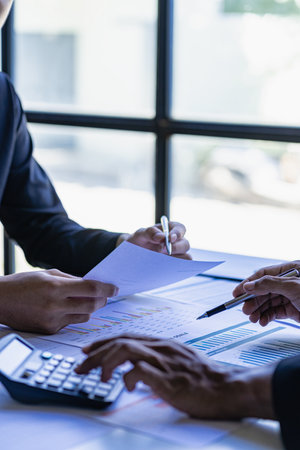 Diverse colleagues brainstorm to discuss financial statistics at an office meeting. Finance, teamwork, data chart concept, graph, financial planning and company vertical imageの写真素材