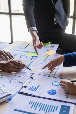 Diverse colleagues brainstorm to discuss financial statistics at an office meeting. Finance, teamwork, data chart concept, graph, financial planning and company vertical imageの写真素材