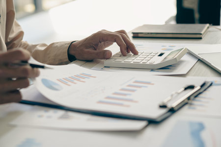 Accountant holding pen and using calculator doing company taxes on wooden table in office tax,...