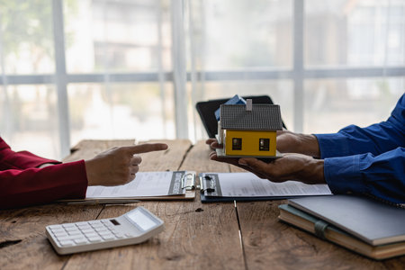 Real estate agents recommend interest rates, discuss the terms of the home purchase agreement, and ask clients to sign paperwork to legalize the contract.の写真素材