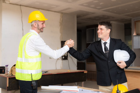 Architect and construction worker engineers shaking hands while working for teamwork and cooperation concept after completing agreement on office construction site.の写真素材