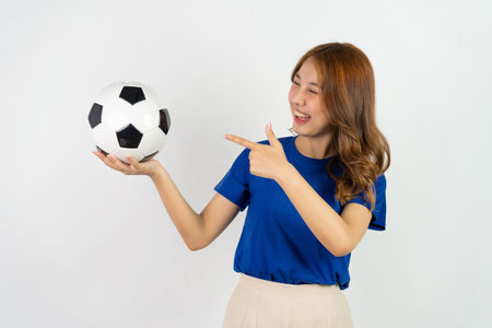 Asian girl in blue t-shirt holding soccer ball posing on white backgroundの写真素材