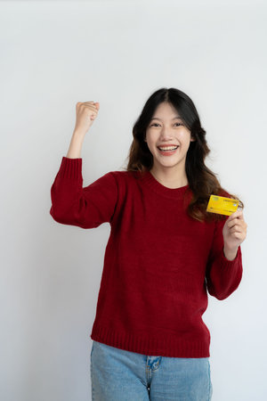 Asian woman holding credit card on white background, happy female smiling and showing credit card for paying online business isolated on backgroundの写真素材