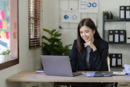 Pretty asian businesswoman using laptop and calculator finance graph document for doing financial mathematics on table, report, accounting, statistics and analytical research conceの写真素材