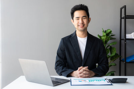 Young asian businessman planning analyzing financial data charts and graphs and successful business laptopの写真素材