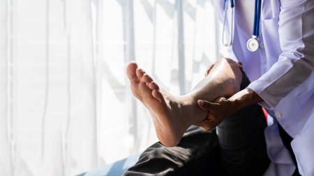 Medical physiotherapist working on male patient's injured leg and treating male athlete patient's injured knee in clinic.の写真素材