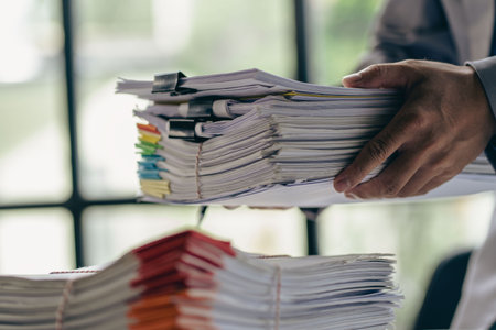 Business administration and information documents on the desk Excessive pile of papers of businessman holding many papers with colorful paperclips in her hand at close upの写真素材