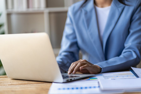 Close up of businesswoman holding pen pointing to paper, business chart for doing math on wooden table, tax, analytical accounting and calculating annual income and expenses, finanの写真素材