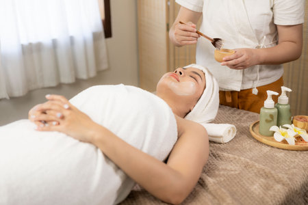 Beautiful young Asian woman getting massage in spa environment, traditional aromatherapy and beauty therapy, close-up photo.の写真素材