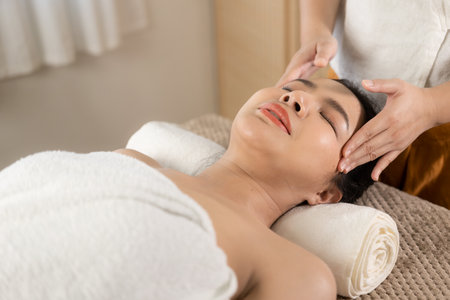 Beautiful young Asian woman getting massage in spa environment, traditional aromatherapy and beauty therapy, close-up photo.の写真素材