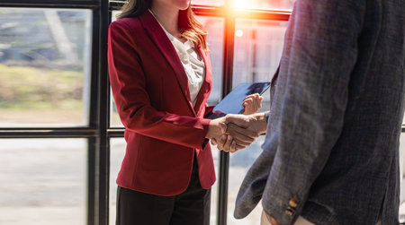 Two confident business men and women shaking hands during success meeting, correspondence, greeting and partnership. Hands holding hands for job interview in modern office Greetingの写真素材
