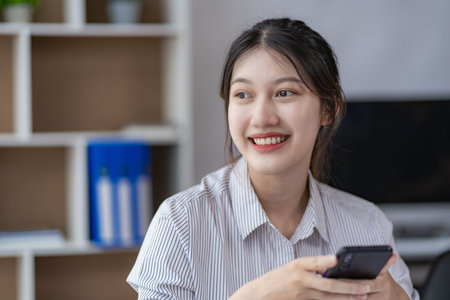Attractive Asian woman talking on the phone with her business partner. Manage business to call...