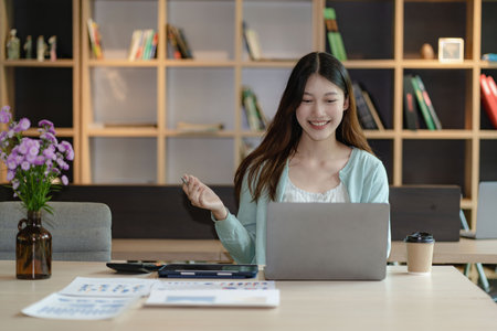 Asian woman using calculator and laptop document for doing financial mathematics on desk, tax,...