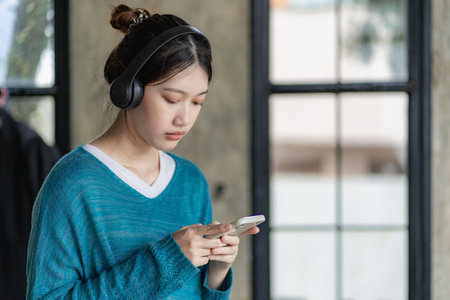 Beautiful Asian woman in casual clothes sitting on sofa using smartphone for social entertainment to relax. smile and laughの写真素材