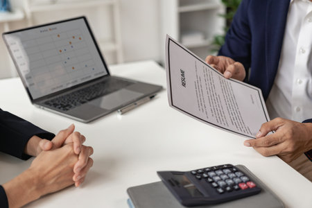 The right candidate gives the interviewer a resume during a job interview in a modern office conference room. woman submitting job application The interviewer reads the resume.の写真素材