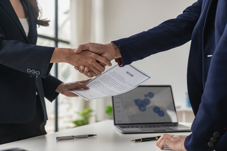 Job interview. Two businessmen shake hands to submit resume documents. HR manager shakes hands congratulating job candidates for successful job application close up picturesの写真素材