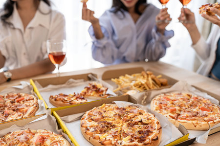 Three Asian girls have a fun pizza party at home at lunchtime.の写真素材