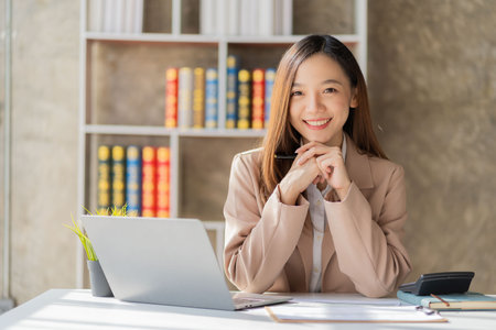 Beautiful asian businesswoman working with laptop and financial documents on desk, company employee holding accounting documents Checking financial data or market reports working iの写真素材