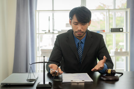 African male lawyer working in law firm justice fights justice Law or judge working with law books, hammer and scales Hammer case report on table in modern officeの写真素材