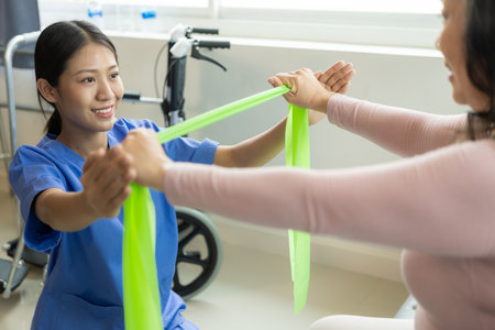 Asian elderly woman doing physiotherapy with nurse support Young woman doing physiotherapy for shoulder muscles at nursing homeの写真素材
