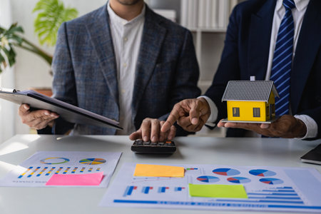 The real estate agent discusses the terms of the home purchase agreement and asks the client to sign paperwork to contract and deliver the home.の写真素材