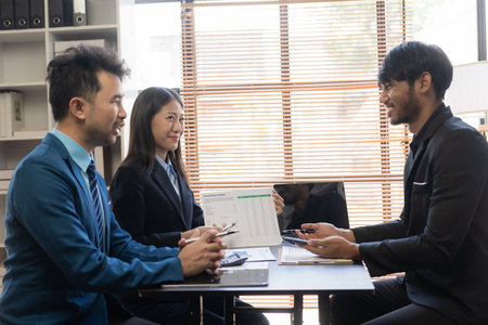 Young asian business people financial analysis meeting brainstorming on new business together with laptop and financial accounting graph papers in officeの写真素材