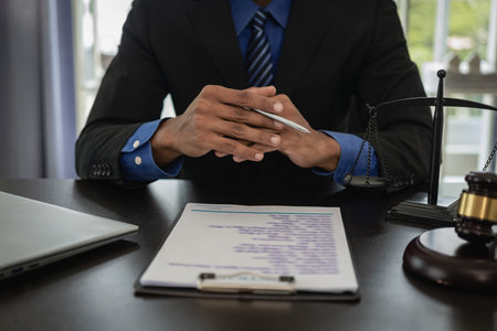 Middle-aged male lawyer working with legal contract documents in court room Justice with tee hammer and black scales on table, law judge consulting and legal services conceptの写真素材