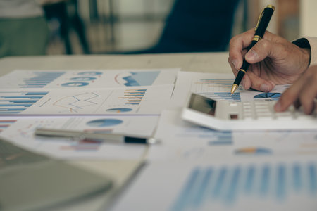 Businessman analyzing investment chart and pressing calculator button to calculate documents...