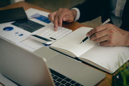 Businessman analyzing investment chart and pressing calculator button to calculate documents Accounting close up image of financial documents on digital tabletの写真素材