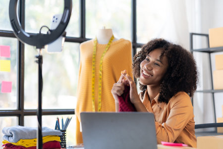 African American girl presents and sells clothes online through live streaming on the internet,...