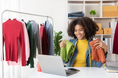 African American girl presents and sells clothes online through live streaming on the internet, chooses a stylish clothing store. Fashion designers draw pictures of new collectionsの写真素材