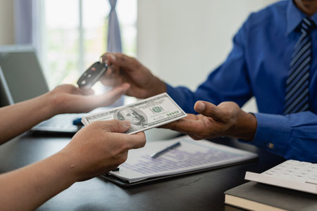 Vehicle rental business concept Close up of hands of car rental agent giving car remote key to customer after signing contract on table, sales and insurance conceptの写真素材