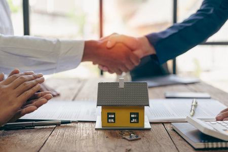 A bank loan officer shakes hands with a customer to congratulate him after approving a home loan. A bank loan officer shakes hands with a customer to congratulate him after signingの写真素材