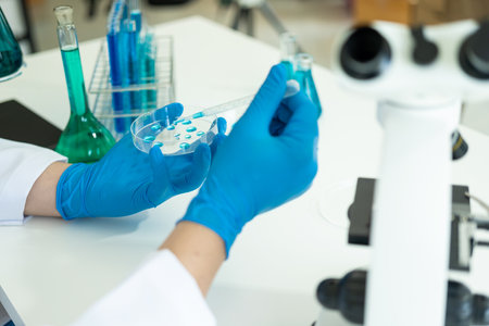 Doctor in mask examining DNA molecule in chemistry lab with scientist examining liquid sample with microscope in chemistry lab Researcher working with sampleの写真素材