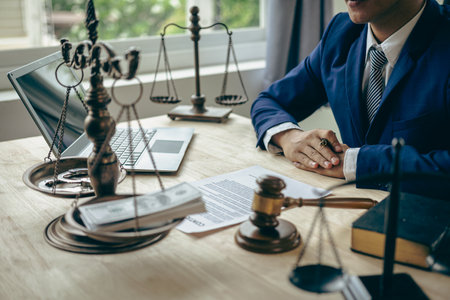Asian male lawyer working in law office with hammer and scale and laptop, contract concept legal proceedingsの写真素材