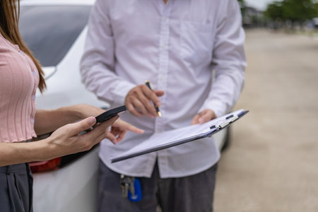 Insurance worker checks damaged car and customer signature in process after traffic accident and insurance concept, close-up photoの写真素材